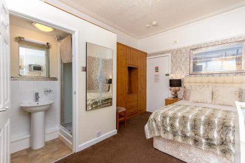 a bedroom with a bed and a sink and a bathroom at Beachcliffe Holiday Apartments in Blackpool