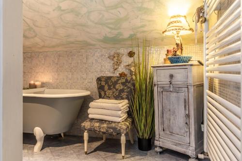 a bathroom with a tub and a chair next to a sink at House Garden Loft in Baricella