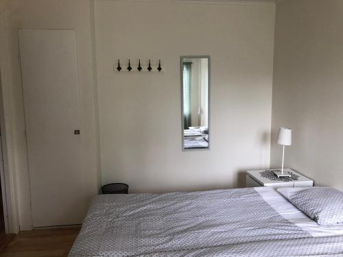 a white bedroom with a bed and a mirror at Bergåsa bed & kitchen Drängsered in Torup