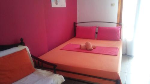 Cama pequeña con almohadas rosas y manta rosa en AGATHA appartments PALIOURIA, en Kokkino Nero