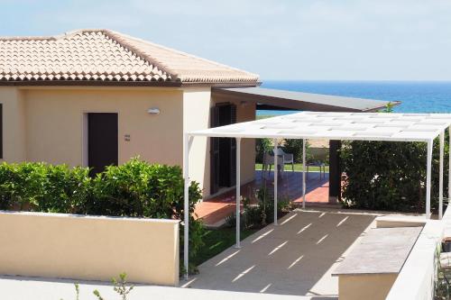 a house with a white awning next to the ocean at Cala Sol in Marina di Modica