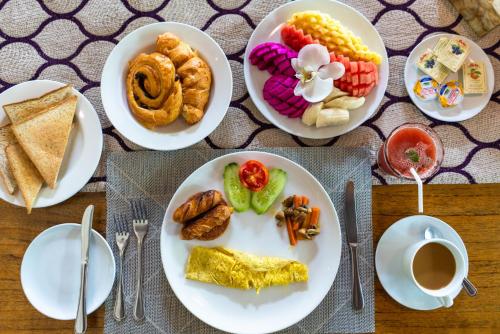 ein Tisch mit Tellern mit Essen und einem Teller mit Snacks in der Unterkunft Boutique hotel villa Cantik and karma beach club in Uluwatu