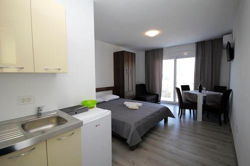 a room with a bed and a kitchen with a table at Rosi`s Apartment in Sutomore