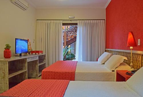 a hotel room with two beds and a television at Pousada Mais Bella in Ilhabela