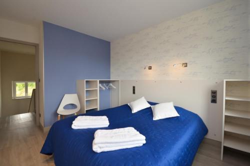una camera da letto con un letto blu e asciugamani di L'annexe de la Pétillante 101 Rue Principale a Soudron