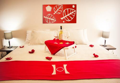 a bed with a red table with glasses and roses on it at HOTEL OLIMPIA in Duitama