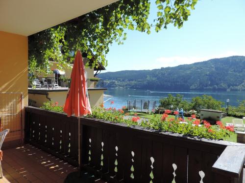 a balcony with a red umbrella and flowers at Pension Sedlak in Millstatt