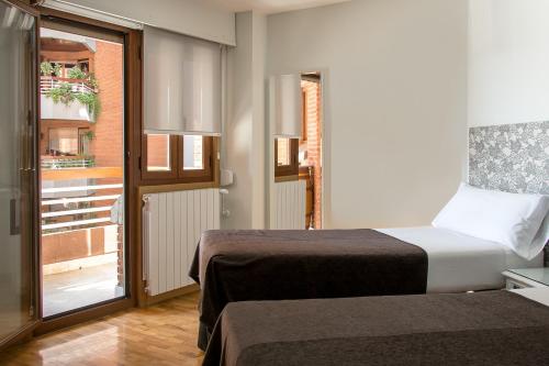 um quarto de hotel com duas camas e uma varanda em Pensión Laurel em Logroño