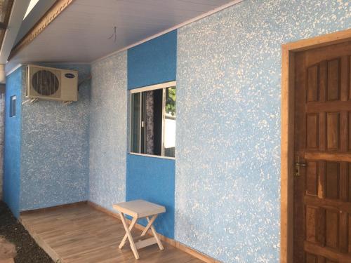 um quarto com uma parede azul com uma janela e um banco em Aconchego Lar Cama e Café em Foz do Iguaçu