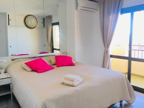 フエンヒロラにあるFuengirola Luxのベッドルーム1室(ピンクの枕と鏡付きのベッド1台付)