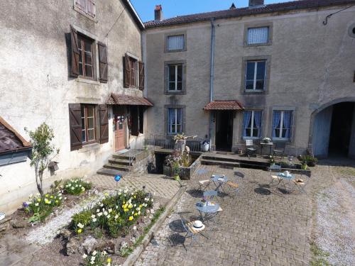 an old building with a courtyard with tables and flowers at La Maison du Notaire - Chambre d'Hôtes - Huisdieren welkom in Melay