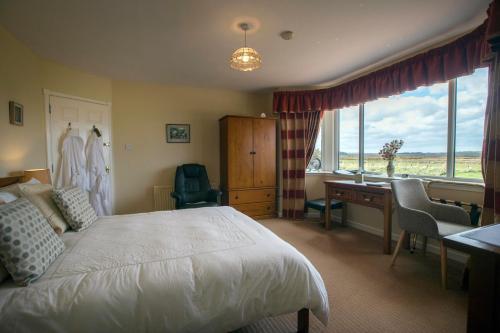 a bedroom with a bed and a desk and a window at The Hawthorns B & B in Mey