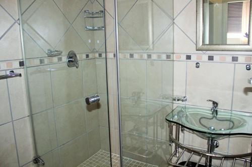 a bathroom with a glass shower with a sink at Uvongo Lucian Blue Flag Beach Apartment in Margate