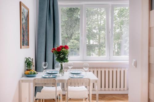 uma mesa branca com cadeiras e um vaso de flores vermelhas em APARTEL Piaseczno em Piaseczno