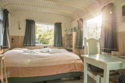 een slaapkamer met een groot bed en een raam bij Pipowagen Elsebein Groningen Westerwolde unieke ligging met eigen tuin en vrij uitzicht over veld naar natuurgebied in Onstwedde