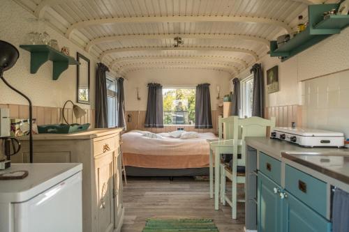 een keuken met een slaapkamer met een bed erin bij Pipowagen Elsebein Groningen Westerwolde unieke ligging met eigen tuin en vrij uitzicht over veld naar natuurgebied in Onstwedde