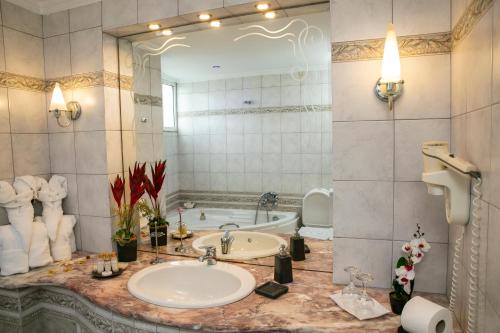 a bathroom with a sink and a tub with a mirror at Hotel Pella in Giannitsa