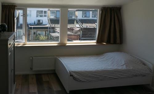 Un dormitorio pequeño con una cama y dos ventanas. en Het Dokhuis, en Middelburg