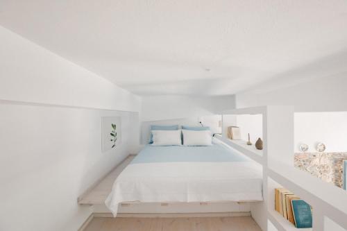 ein weißes Zimmer mit einem Bett und einem Bücherregal in der Unterkunft Achinos guest house, Skopelos in Skopelos