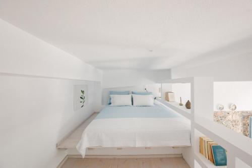 a white room with a bed and a book shelf at Achinos guest house, Skopelos in Skopelos Town