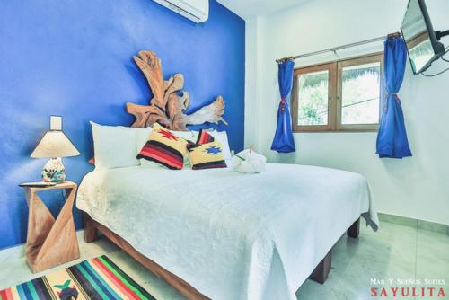a bedroom with a large bed with blue walls at Mar y Sueños in Sayulita