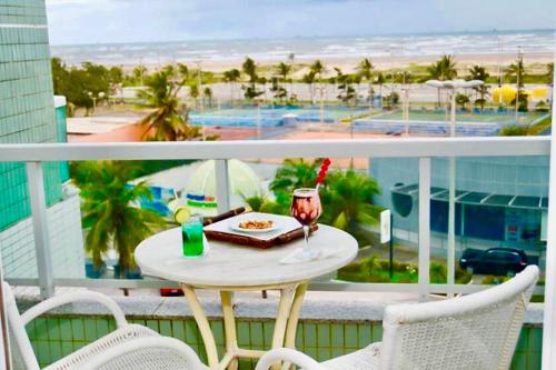 a table with a plate of food and a drink on a balcony at Real Classic Hotel in Aracaju