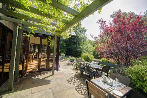 an outdoor patio with tables and chairs and trees at Willowbeck Lodge Boutique Hotel in Carlisle