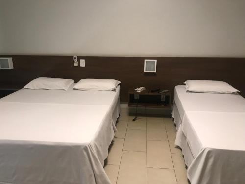 two beds in a hotel room with at Oásis Hotel in Araguaína