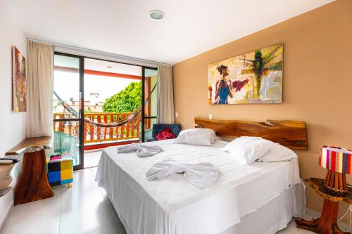 a bedroom with a white bed and a balcony at Xainã Pousada de Charme in Cumbuco