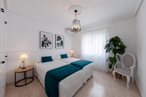 a white bedroom with a large bed and a chair at Villa Sunset in Ciudad Quesada