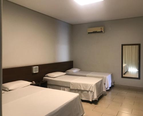 a hospital room with two beds and a mirror at Oásis Hotel in Araguaína