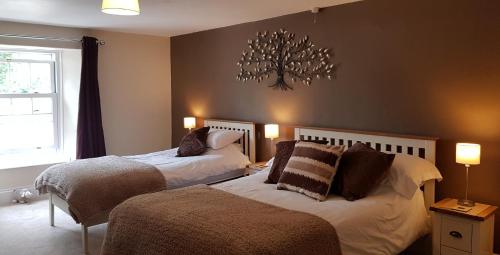 1 dormitorio con 2 camas y un árbol en la pared en The Greyhound Inn en Bedale