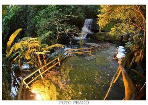 a bridge over a river with a waterfall at Pousada Vale Dos Figos in Urussanga