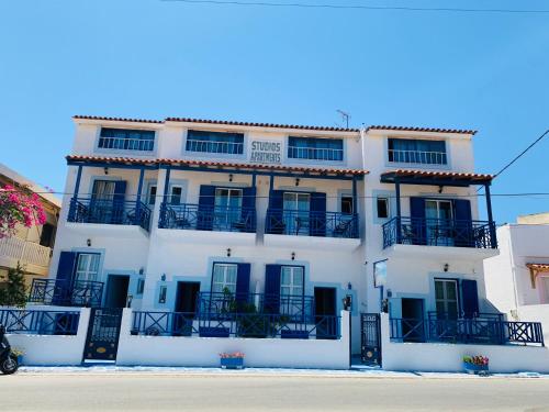 a white building with blue windows and balconies at Angistri's panorama apartments in Skala