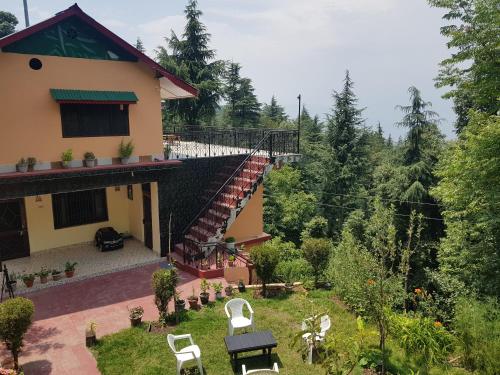 a house with a yard with white chairs and trees at Aditya Homestay Dalhousie in Dalhousie