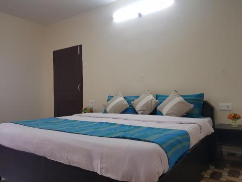 a bedroom with a large bed with blue and white pillows at Aditya Homestay Dalhousie in Dalhousie