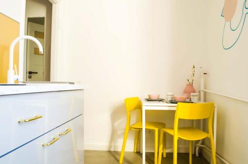 cocina con mesa pequeña y 2 sillas amarillas en New Life Apartment next to Metro Station, en Varsovia