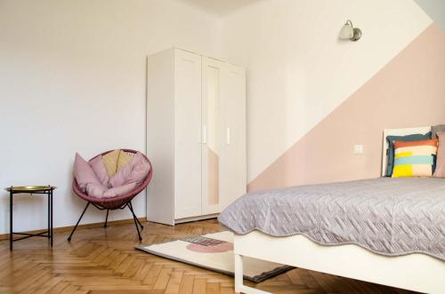 1 dormitorio con 1 cama y 1 silla rosa en New Life Apartment next to Metro Station, en Varsovia