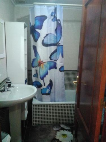 a bathroom with a shower curtain with butterflies on it at Cabañaquinta Senderista in Aller