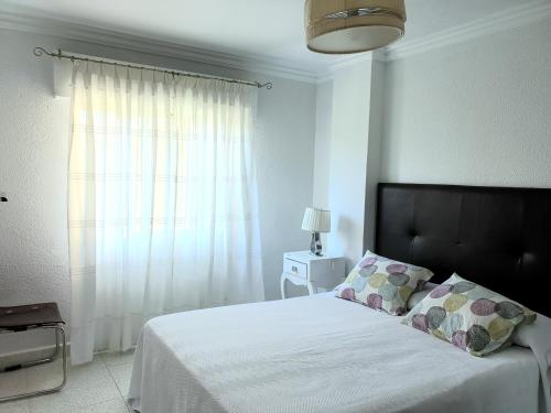 een slaapkamer met een wit bed en een raam bij By The Beach in Málaga