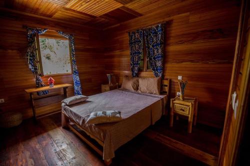 ein Schlafzimmer mit einem Bett in einem Holzzimmer in der Unterkunft Roça Saudade Guest House in Trindade