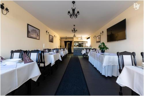 a row of tables in a restaurant with white linens at Pásztó Fogadó in Pásztó