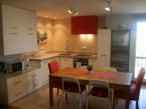 una cocina con mesa y sillas y una cocina con armarios blancos. en Bienvenidos a vuestra casa!, en Sansoáin