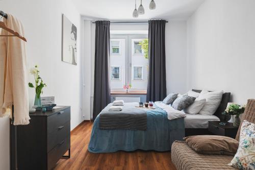1 dormitorio con cama, sofá y ventana en Mokotow Accommodation P&O Serviced Apartments, en Varsovia