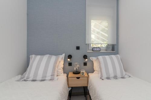 two beds with white pillows and a night stand in a bedroom at Apartments Flora Trogir in Trogir