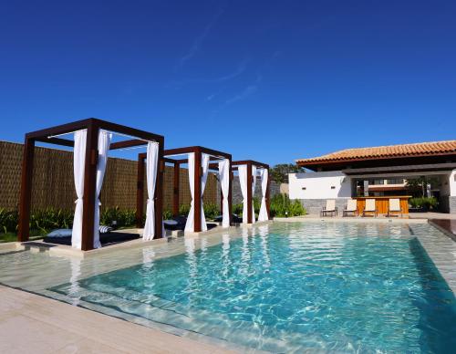 a swimming pool with pillars in the middle at Hotel Aretê in Búzios