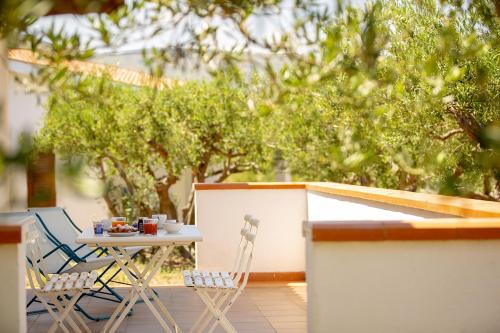 a table and chairs on a patio with trees at Casale la Macina Residence Scopello in Scopello