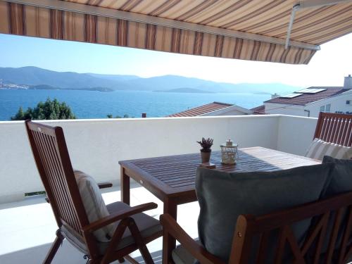 una mesa y sillas en un balcón con vistas al océano en Apartmani More Komarna, en Komarna