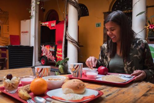 een vrouw die aan een tafel zit eten bij Colors House in Sucre
