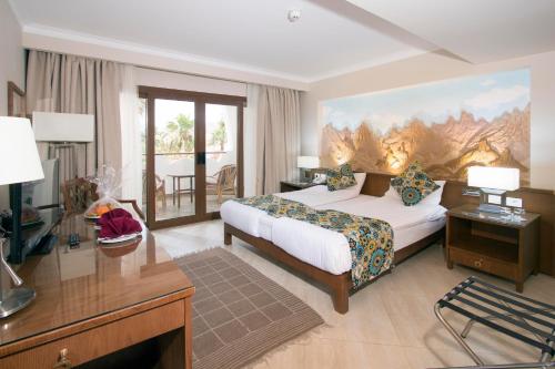 ein Hotelzimmer mit einem Schlafzimmer mit einem Bett und einem Schreibtisch in der Unterkunft Swiss Inn Resort Dahab in Dahab
